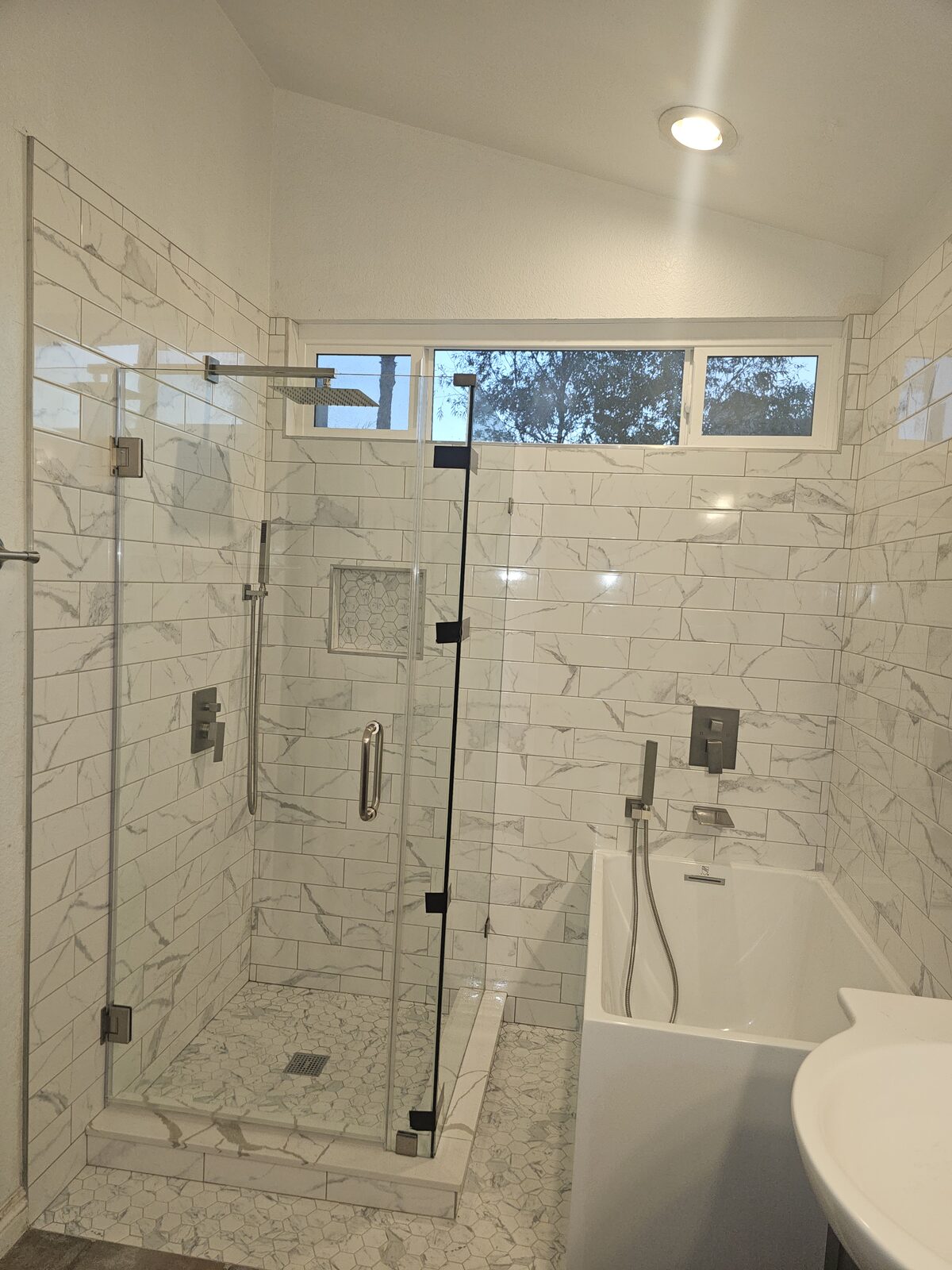 Bathroom with frameless glass shower, marble-look subway tile, hexagon mosaic shower floor and alcove soaking tub
