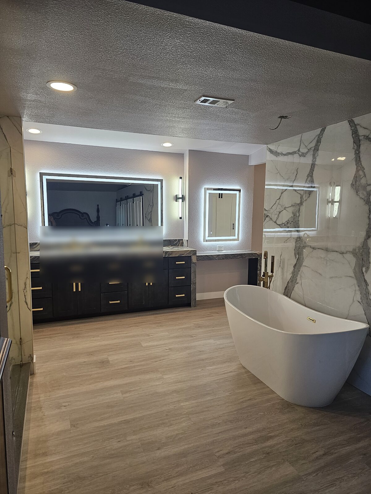 Master bathroom remodel in Yorba Linda with freestanding slipper tub, book-matched marble slab wall, backlit LED mirrors and a dark vanity with brass hardware