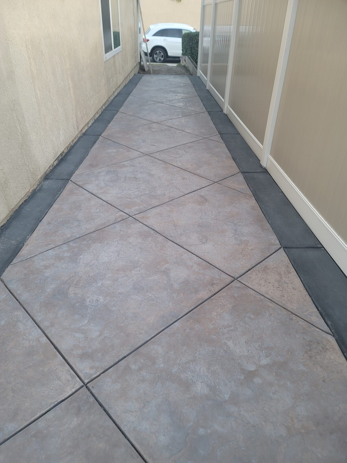 Stamped concrete side-yard walkway in Yorba Linda with diamond pattern and contrasting charcoal border